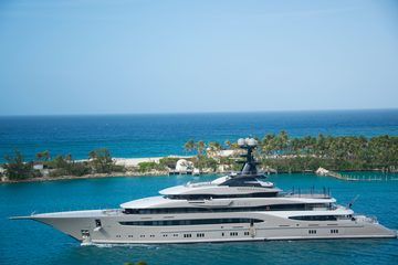 A large yacht passing a palm-covered point