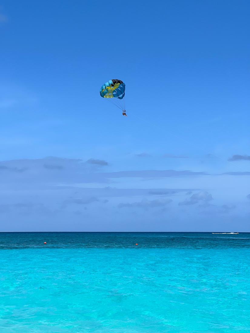 A parasailer above bright turquoise sea under a deep blue sky