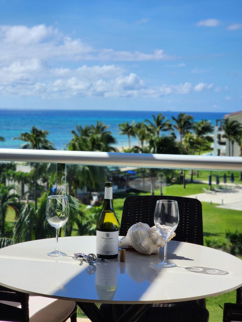 Balcony table with wine glasses and a conch shell overlooking palm trees and the sea