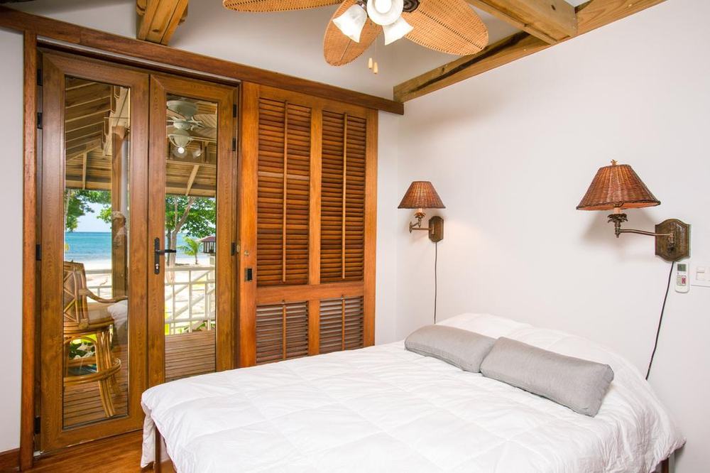 Bedroom with wood shutters and doors opening to a beach view