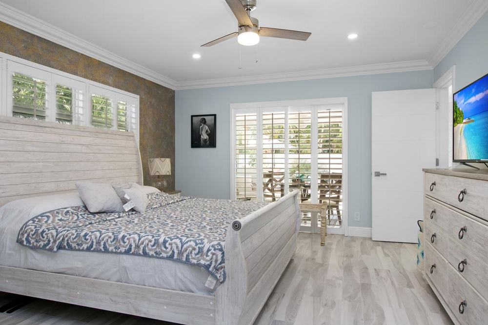 Bright bedroom with plantation shutters and sliding doors to a patio