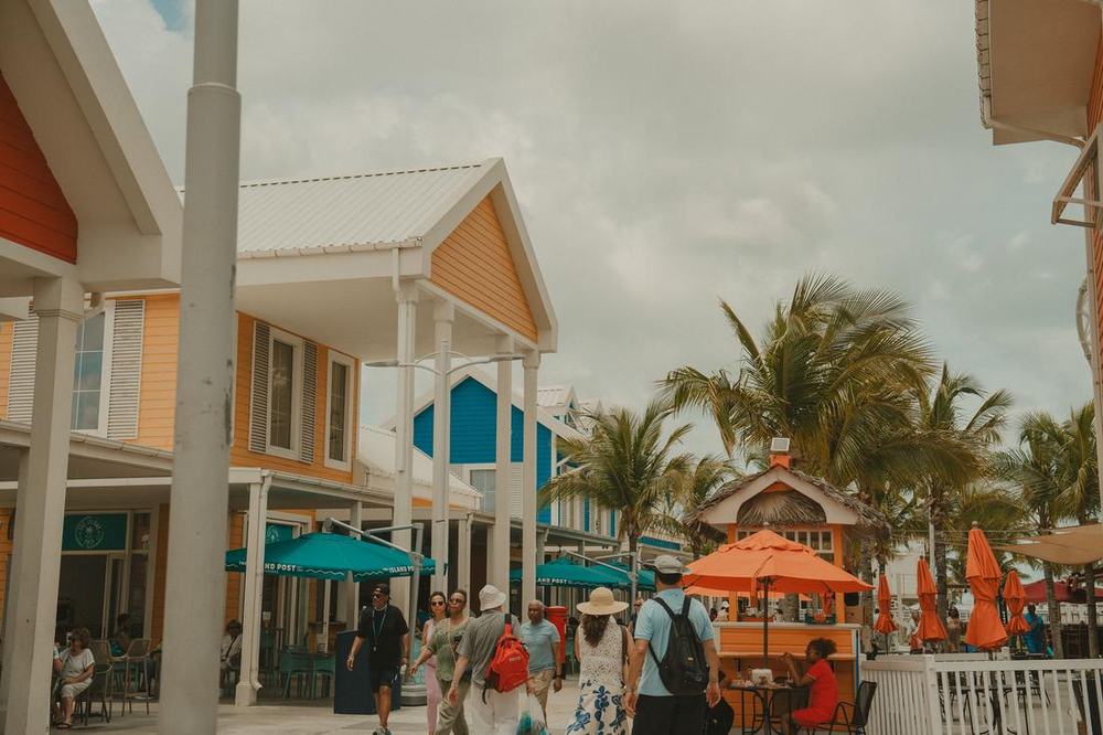 Colourful island shops and umbrellas with visitors strolling past palm trees