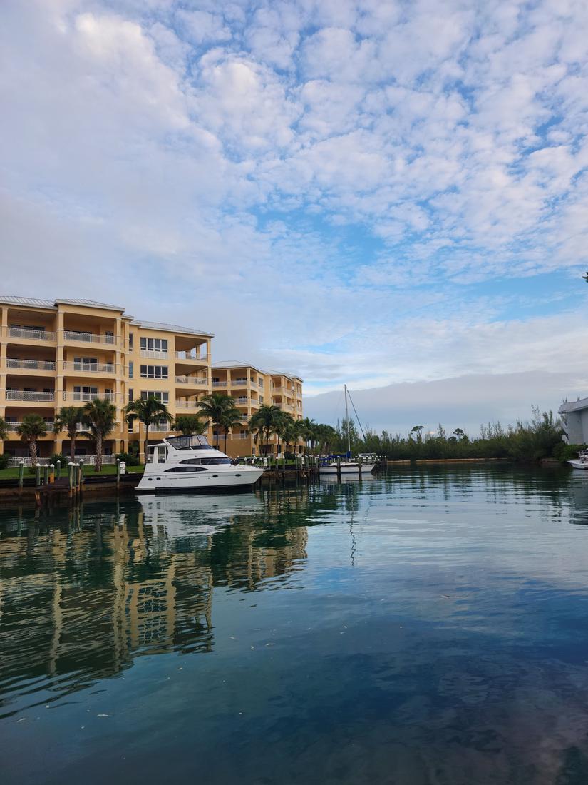 Yellow waterfront condo buildings beside a quiet marina with a motor yacht